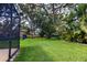 Spacious backyard featuring a well-maintained lawn, mature trees, and secure black metal fencing at 8901 Eagle Watch Dr, Riverview, FL 33578
