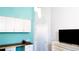 Clean bedroom with a blue accent wall, built-in desk, TV, and overhead storage at 8901 Eagle Watch Dr, Riverview, FL 33578