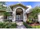 Inviting front entrance featuring an arched portico, brick accents, and lush landscaping at 8901 Eagle Watch Dr, Riverview, FL 33578