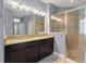 Bathroom featuring double sinks, granite countertops, and a glass-enclosed shower at 9275 Bella Vita Cir, Land O Lakes, FL 34637
