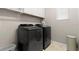 Modern laundry room with black washer and dryer, white cabinets, and neutral walls at 9275 Bella Vita Cir, Land O Lakes, FL 34637