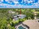A scenic aerial view of a lovely two-story home with a screened-in pool, set amongst lush green landscaping at 9808 Milano Dr, Trinity, FL 34655