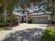 Charming exterior featuring a brick driveway, multi-car garage, and beautiful landscaping with flowering trees at 9808 Milano Dr, Trinity, FL 34655