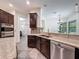 Bright kitchen showcasing a stainless dishwasher, granite countertops, a double sink, and dark wood cabinets at 9808 Milano Dr, Trinity, FL 34655