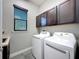 Laundry room featuring modern washer, dryer, grey tile floors, and dark cabinets at 9808 Milano Dr, Trinity, FL 34655