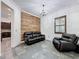 Comfortable living room with a rustic wood accent wall, tile flooring, and plush leather seating at 9808 Milano Dr, Trinity, FL 34655