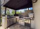 A built-in grill and mini-fridge highlight the outdoor kitchen in this shaded outdoor space at 9808 Milano Dr, Trinity, FL 34655