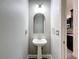 Powder room with pedestal sink, arched mirror, and neutral walls at 9808 Milano Dr, Trinity, FL 34655