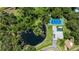 Aerial view of property with pond and tennis court, set amongst mature trees at 13710 Westshire Dr, Tampa, FL 33618