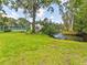 Manicured backyard with lush green lawn and tennis court in the background at 13710 Westshire Dr, Tampa, FL 33618