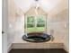 A luxurious bathroom boasting a soaking tub with natural light and travertine tile surround at 13710 Westshire Dr, Tampa, FL 33618