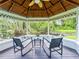 A wooden gazebo features wicker chairs and overlooks a lush lawn and pond at 13710 Westshire Dr, Tampa, FL 33618