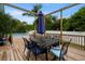 Outdoor dining on wooden deck with large metal table, chairs and umbrella, overlooking pool at 14030 79Th Ave, Seminole, FL 33776