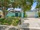 Charming turquoise home featuring a well-manicured lawn, mature trees, and a white gravel driveway at 14030 79Th Ave, Seminole, FL 33776