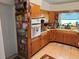 Cozy kitchen featuring built-in shelving, wooden cabinets, and light tile floors under natural light from the window at 1448 Temple St, Clearwater, FL 33756
