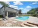 Large backyard with a pool, lush landscaping, a covered patio, and stone pavers, ideal for outdoor living at 1669 Feather Grass Loop, Lutz, FL 33558