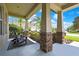 Charming covered front porch featuring comfortable seating and stylish stone columns with a well-landscaped view at 1669 Feather Grass Loop, Lutz, FL 33558