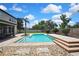 Sparkling pool surrounded by a stone patio, lush landscaping, and a spacious yard, perfect for outdoor enjoyment at 1669 Feather Grass Loop, Lutz, FL 33558