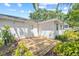 A backyard featuring a wood deck, complemented by lush tropical landscaping and an adjacent white exterior wall at 2320 Harn Blvd, Clearwater, FL 33764