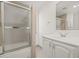 A bright bathroom featuring a shower with glass door, a modern vanity, and neutral colored tiling at 2320 Harn Blvd, Clearwater, FL 33764