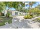 White brick home with green shutters and a long driveway framed by mature trees and a well-manicured lawn at 2320 Harn Blvd, Clearwater, FL 33764