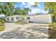 White brick single-story home with green shutters features a spacious driveway leading to a two-car garage at 2320 Harn Blvd, Clearwater, FL 33764