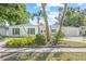 Charming white brick home with green shutters, palm trees, and lush landscaping creates inviting curb appeal at 2320 Harn Blvd, Clearwater, FL 33764