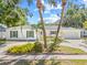 White brick home with green shutters, palm trees, and lush landscaping creates an inviting entrance at 2320 Harn Blvd, Clearwater, FL 33764