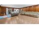Spacious living room with wood paneling, hardwood floors, and an inviting sectional sofa at 23327 Christian Cir, Brooksville, FL 34601