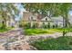 This home features a lush lawn, mature tree, brick driveway, and a charming facade with dormer windows at 2512 W Jetton Ave, Tampa, FL 33629