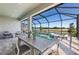 Inviting covered patio with outdoor dining and a screened pool and spa overlooking a scenic lake at 27124 Capri Shores Cir, Englewood, FL 34223