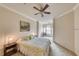 A serene bedroom with a floral bedspread, complemented by a ceiling fan and a seating area near a large window at 2733 Via Cipriani # 830B, Clearwater, FL 33764