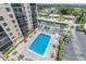 An aerial shot of a community pool with tables, lounge chairs, tropical plants, a parking lot, and condos at 2901 26Th W St # 815, Bradenton, FL 34205