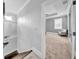A hallway leads to a gray primary bedroom featuring a tray ceiling, ceiling fan, and carpet at 3013 W Crest Ave, Tampa, FL 33614