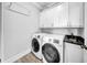 Bright laundry room featuring modern machines, white cabinets, black countertop, and stylish flooring at 3013 W Crest Ave, Tampa, FL 33614