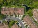 An aerial view of townhomes with brown roofs with street access and views of a pond and surrounding green space at 3077 Branch Dr, Clearwater, FL 33760