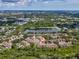 Aerial view of tan townhomes with lush green surroundings and a serene lake nearby at 3077 Branch Dr, Clearwater, FL 33760