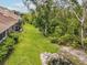 A backyard with lush green grass, mature trees, and access to a pond at 3077 Branch Dr, Clearwater, FL 33760