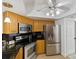 Well-equipped kitchen with stainless steel appliances, wood cabinets, and neutral tile flooring at 3077 Branch Dr, Clearwater, FL 33760