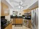 Modern kitchen with stainless steel appliances, wood cabinetry, black countertops, and tile flooring at 3077 Branch Dr, Clearwater, FL 33760