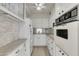 Galley kitchen with white cabinetry, modern appliances, and stylish backsplash at 31 Island Way # 502, Clearwater Beach, FL 33767