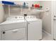 Well-lit laundry room with modern white washer and dryer units and ample shelving for storage at 3519 Heards Ferry Dr, Tampa, FL 33618