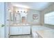 Bathroom featuring double sinks, a large mirror with Hollywood lighting, and a large garden tub at 37526 New Horizons Blvd, Zephyrhills, FL 33541