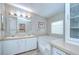Bathroom featuring double sinks, a large mirror with Hollywood lighting, and a large garden tub at 37526 New Horizons Blvd, Zephyrhills, FL 33541