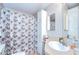 Bathroom with a shower, neutral leaf-patterned shower curtain and built in storage at 37526 New Horizons Blvd, Zephyrhills, FL 33541