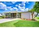 Well-manicured lawn and landscaped yard complements the covered parking of this cozy home at 37526 New Horizons Blvd, Zephyrhills, FL 33541