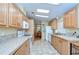 Galley kitchen with tile backsplash, matching floors, wooden cabinets, and white appliances at 37526 New Horizons Blvd, Zephyrhills, FL 33541