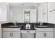 Bathroom with double sinks, granite countertop, white cabinets, and a large frameless mirror at 3999 Burdick Loop, Odessa, FL 33556