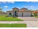 Charming front exterior features a three-car garage and tiled roof, situated on a well-manicured lawn at 3999 Burdick Loop, Odessa, FL 33556