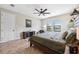 Light filled main bedroom features a fan, herringbone floors, and furniture with an organic color palette at 3999 Burdick Loop, Odessa, FL 33556